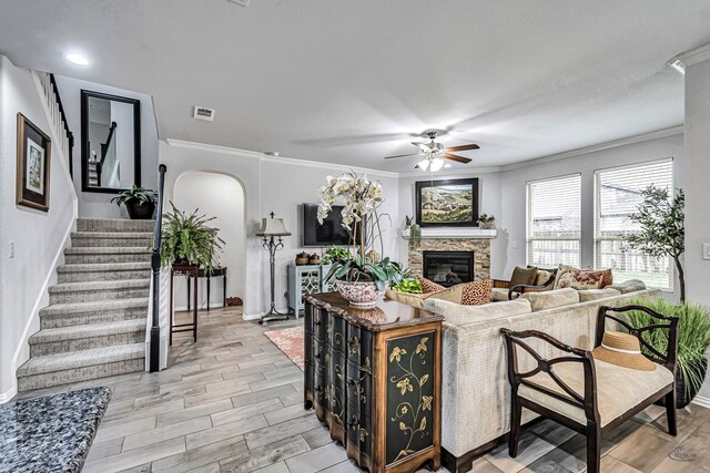 7016 Spur Ranch Rd, Odessa, TX 79765 - living area featuring arched walkways, a ceiling fan, a fireplace, crown molding, and stairway