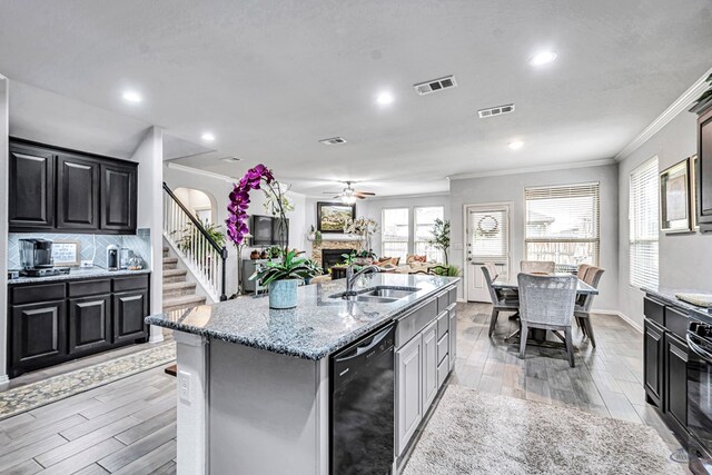 7016 Spur Ranch Rd, Odessa, TX 79765 - kitchen with black dishwasher, ornamental molding, ceiling fan, a stone fireplace, and light wood-style flooring