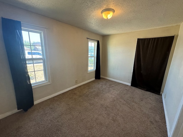 carpeted empty room with a textured ceiling