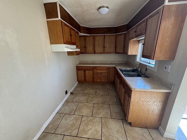 kitchen featuring a textured ceiling, light tile patterned floors, and sink