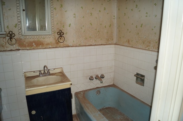 708 W Yukon Rd, Odessa, TX 79764 - full bath with a bathtub, vanity, tile walls, wallpapered walls, and wainscoting