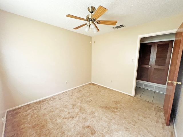 unfurnished room featuring ceiling fan, light colored carpet, and a textured ceiling