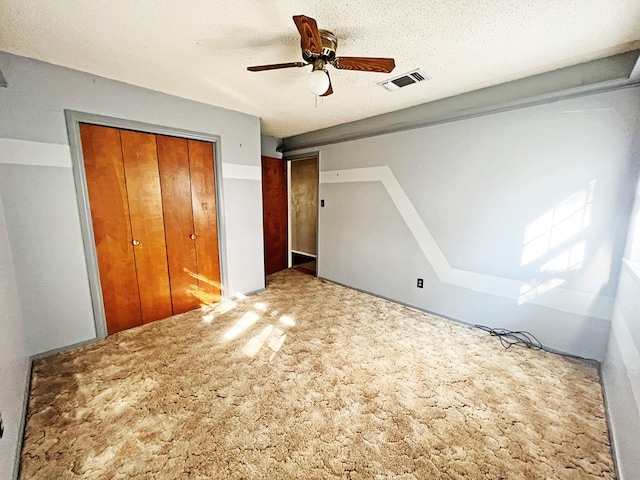 unfurnished bedroom with ceiling fan, a closet, carpet floors, and a textured ceiling