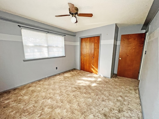 unfurnished bedroom featuring a textured ceiling, ceiling fan, light carpet, and a closet