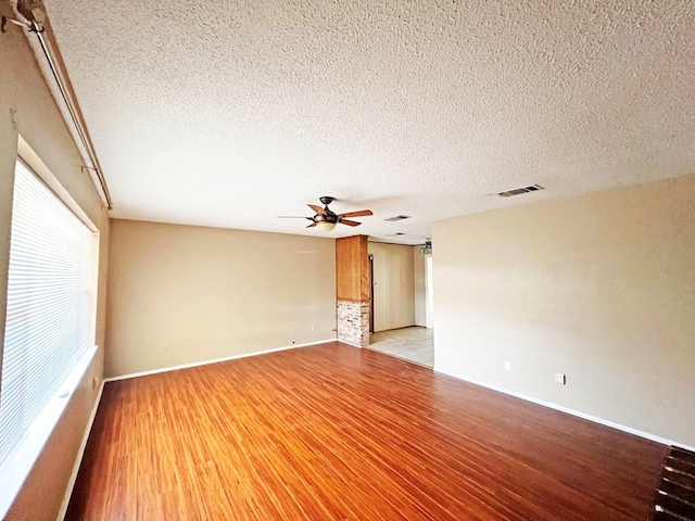 unfurnished room with a textured ceiling, light wood-type flooring, and ceiling fan