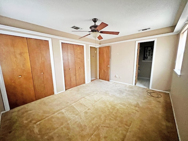 unfurnished bedroom featuring ceiling fan and two closets