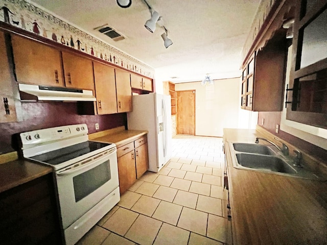 kitchen featuring sink, track lighting, and white appliances