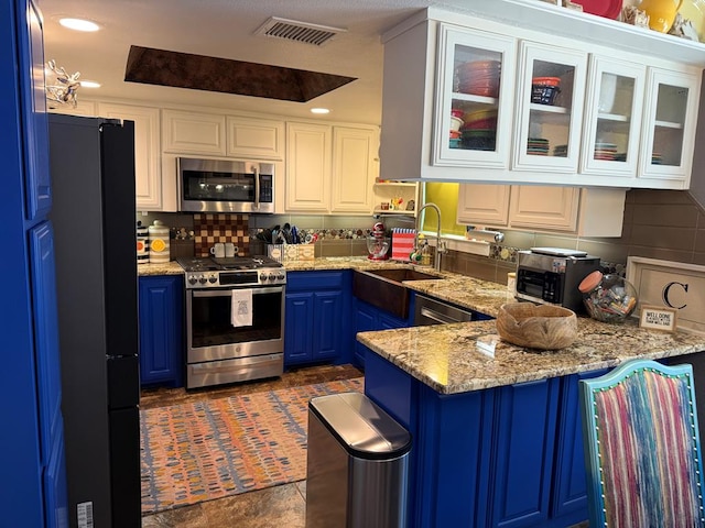 kitchen featuring blue cabinets, white cabinetry, appliances with stainless steel finishes, and sink