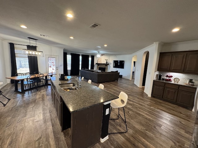 7001 La Escalera Ct, Odessa, TX 79765 - kitchen with dark wood-style flooring, dark brown cabinets, arched walkways, crown molding, and recessed lighting