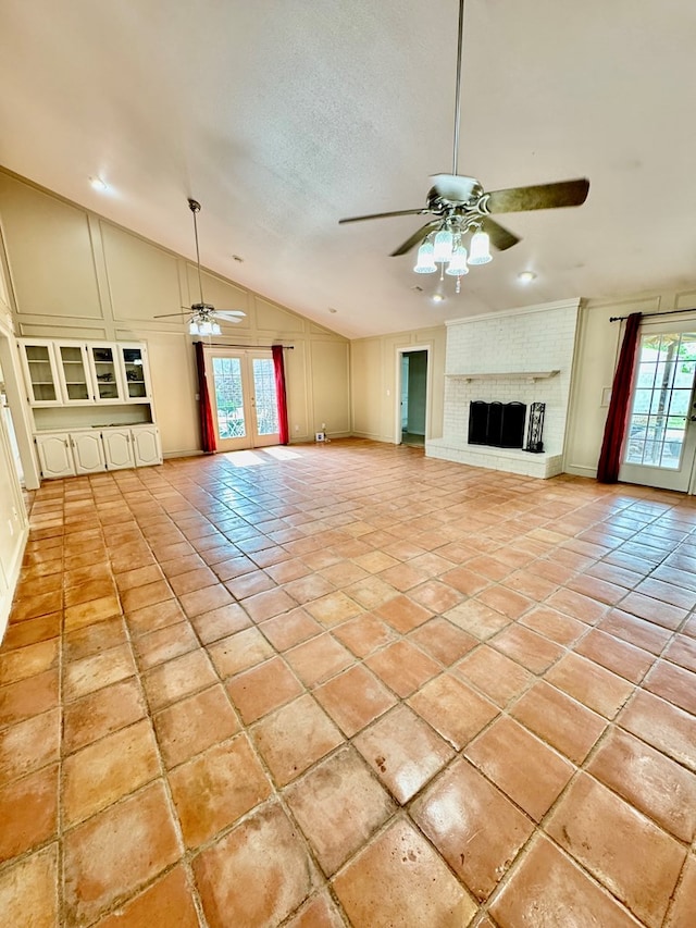 6305 Mecca St, Odessa, TX 79762 - unfurnished living room with a ceiling fan, vaulted ceiling, light tile patterned floors, a brick fireplace, and baseboards