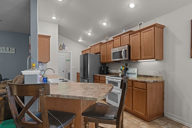 1012 Duke Ave, Odessa, TX 79765 - kitchen featuring appliances with stainless steel finishes, a kitchen breakfast bar, brown cabinetry, a peninsula, and vaulted ceiling
