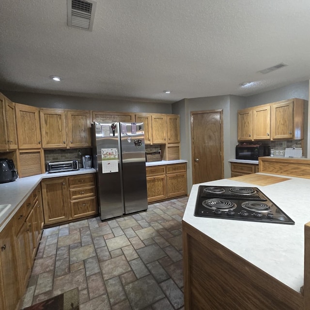 9935 W Yukon Rd, Odessa, TX 79764 - kitchen with black appliances, decorative backsplash, light countertops, recessed lighting, and a textured ceiling
