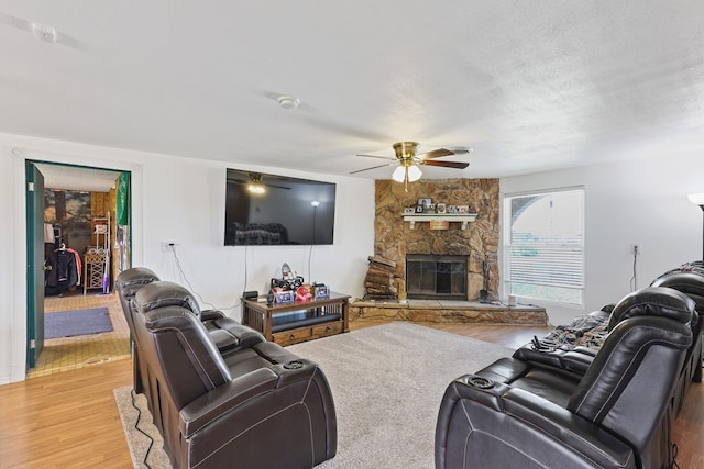 1908 W 36th St, Monahans, TX 79756 - living area featuring light wood-type flooring, a ceiling fan, a fireplace, and a textured ceiling