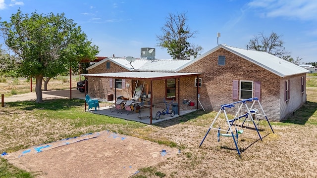1908 W 36th St, Monahans, TX 79756 - back of property featuring a yard, a patio, brick siding, and metal roof