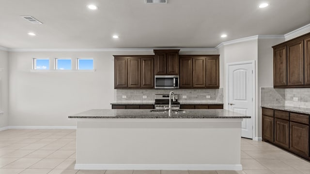 kitchen with dark brown cabinets, sink, stainless steel appliances, and a kitchen island with sink