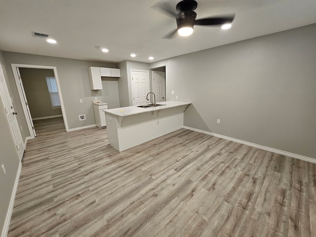 3819 Robertson Ave, Odessa, TX 79764 - kitchen featuring a peninsula, light wood finished floors, a ceiling fan, a kitchen bar, and white cabinets