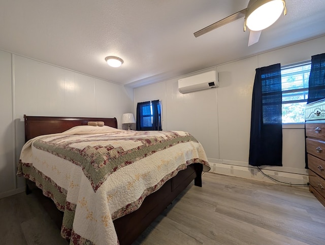 403 Commerce St, Fort Davis, TX 79734 - bedroom featuring a wall mounted AC, a decorative wall, a ceiling fan, and wood finished floors