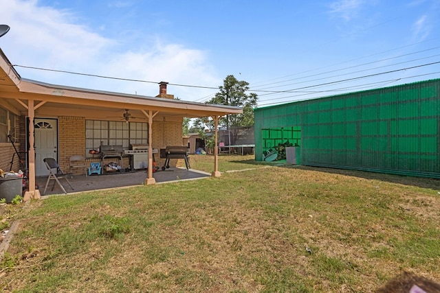 view of grassy yard featuring a trampoline, a patio area, and ceiling fan