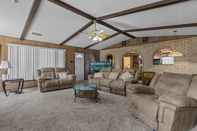 living area with a textured ceiling, arched walkways, wood walls, brick wall, and carpet floors