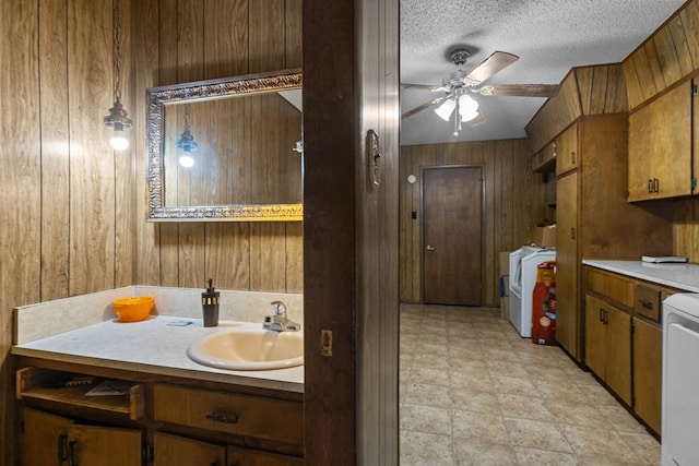 bathroom featuring washer / clothes dryer, ceiling fan, wood walls, a textured ceiling, and vanity