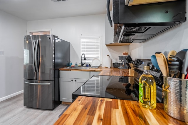 411 N San Jacinto St, Odessa, TX 79762 - kitchen featuring freestanding refrigerator, butcher block countertops, light wood-style flooring, extractor fan, and electric range oven