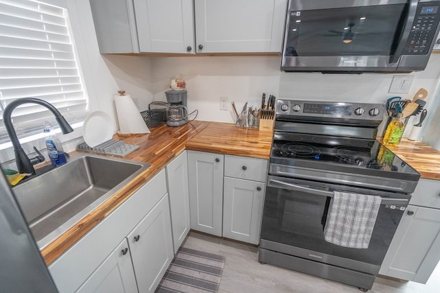 411 N San Jacinto St, Odessa, TX 79762 - kitchen with stainless steel appliances, butcher block counters, light wood finished floors, and white cabinetry