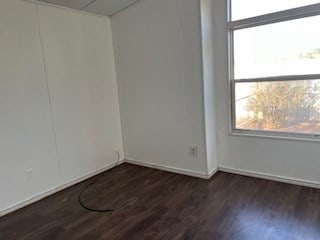 7720 W 26th St, Odessa, TX 79764 - unfurnished room with plenty of natural light, dark wood-type flooring, and baseboards