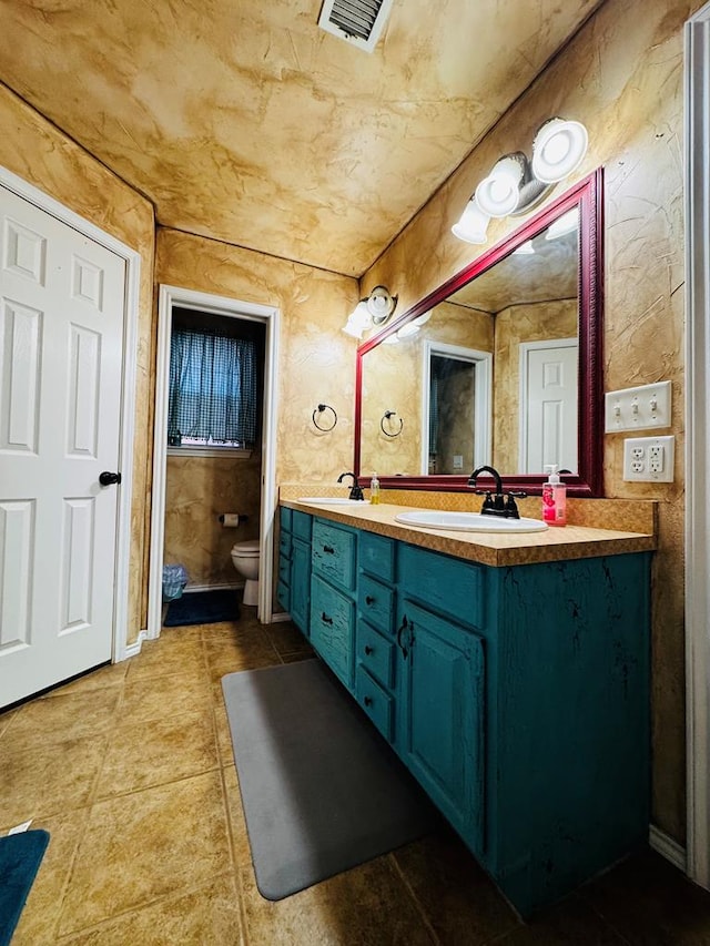 bathroom featuring visible vents, toilet, double vanity, tile patterned floors, and a sink