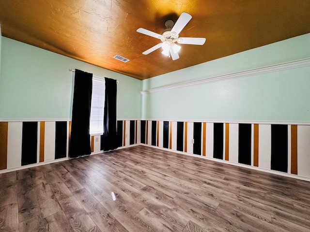 spare room featuring wood finished floors, visible vents, and ceiling fan