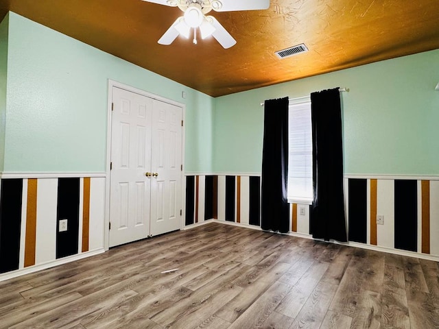 unfurnished room featuring visible vents, wood finished floors, and a ceiling fan