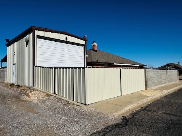 view of home's exterior featuring a garage, an outbuilding, and fence