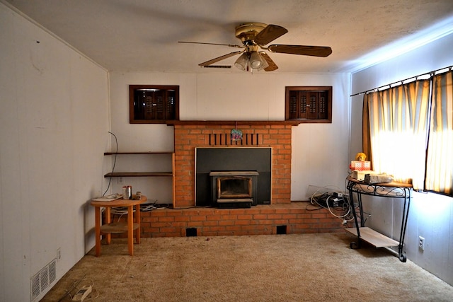 carpeted living room with a wood stove, visible vents, and a ceiling fan