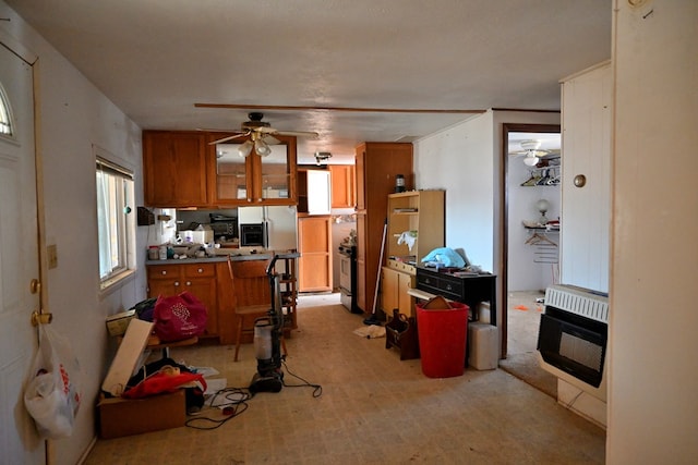 kitchen with ceiling fan, heating unit, stove, brown cabinets, and glass insert cabinets