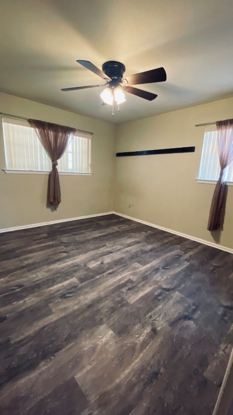 unfurnished room with wood finished floors, baseboards, and ceiling fan