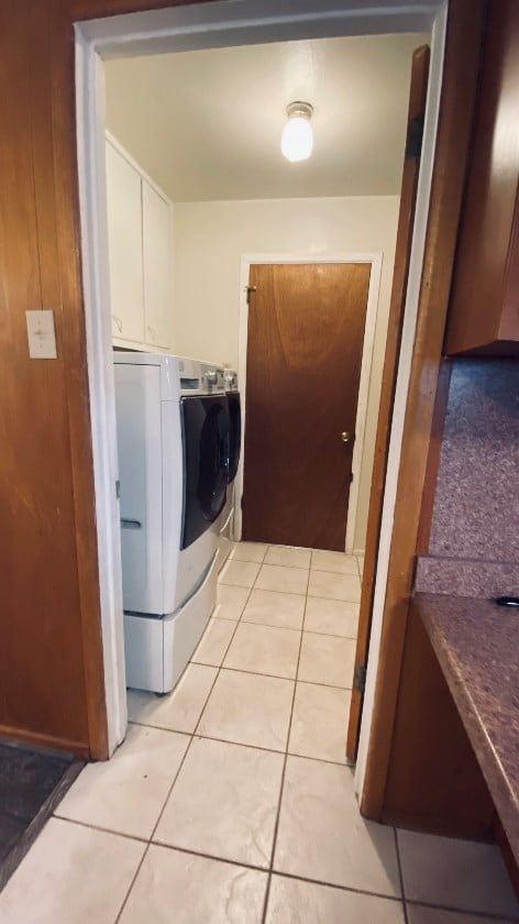 laundry room featuring washer and dryer, cabinet space, and light tile patterned floors