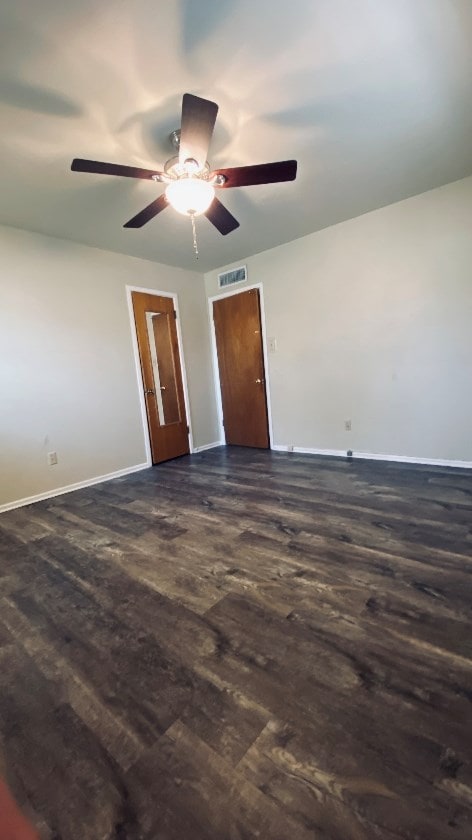 spare room featuring baseboards and dark wood-style flooring