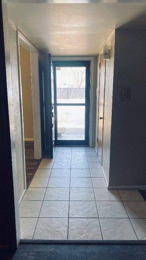 doorway featuring tile patterned flooring and a textured ceiling