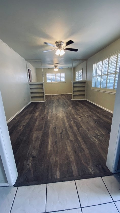 unfurnished living room featuring wood finished floors, baseboards, and ceiling fan