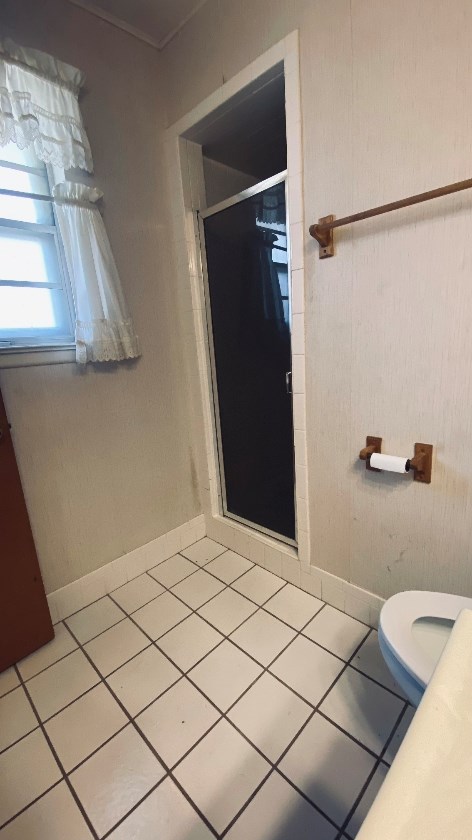 bathroom with a stall shower, toilet, and baseboards