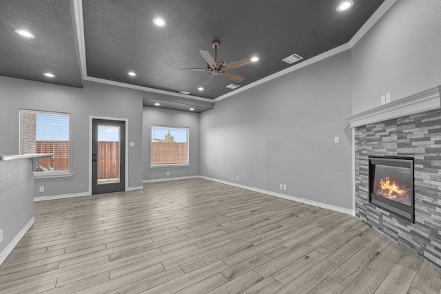 unfurnished living room with wood finished floors, a tiled fireplace, a textured ceiling, visible vents, and ceiling fan