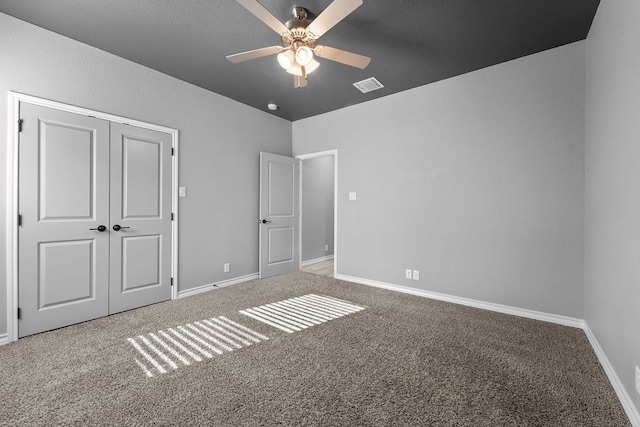 unfurnished bedroom featuring a ceiling fan, a closet, carpet, baseboards, and visible vents