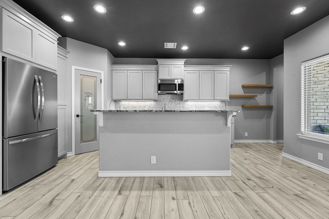 kitchen featuring stainless steel appliances, decorative backsplash, white cabinets, and light wood-style floors