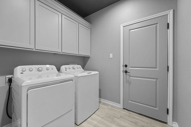 laundry area with washing machine and clothes dryer, light wood-style floors, cabinet space, and baseboards