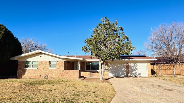 ranch-style home featuring a garage, a front lawn, and solar panels