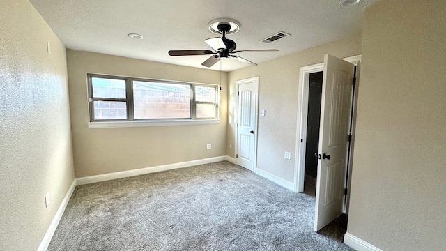 unfurnished bedroom featuring ceiling fan, light colored carpet, and a textured ceiling