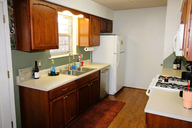 kitchen featuring a sink, white appliances, dark wood-style floors, and light countertops