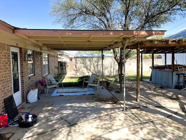 view of patio with a hot tub and fence
