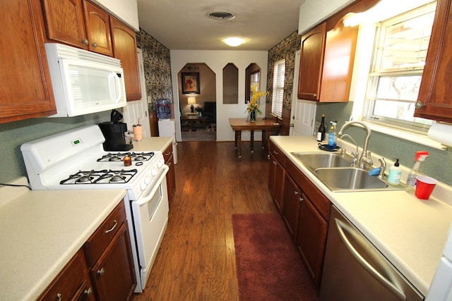kitchen featuring white appliances, a sink, dark wood-style flooring, and light countertops
