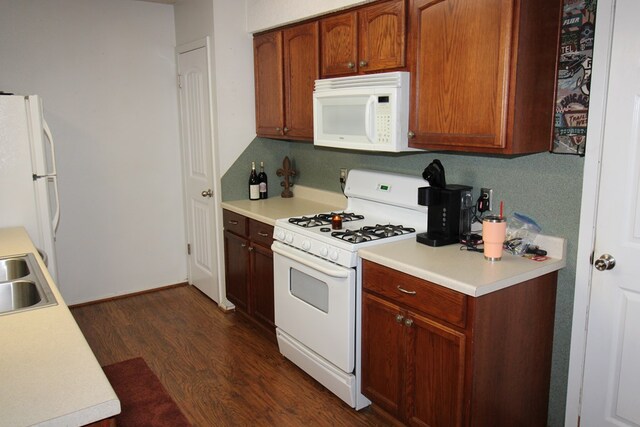 kitchen with white appliances, dark wood-style flooring, light countertops, and a sink