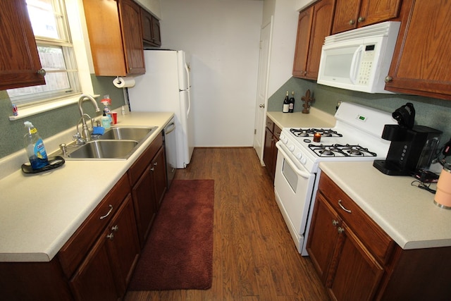 kitchen with white appliances, a sink, dark wood-style floors, and light countertops